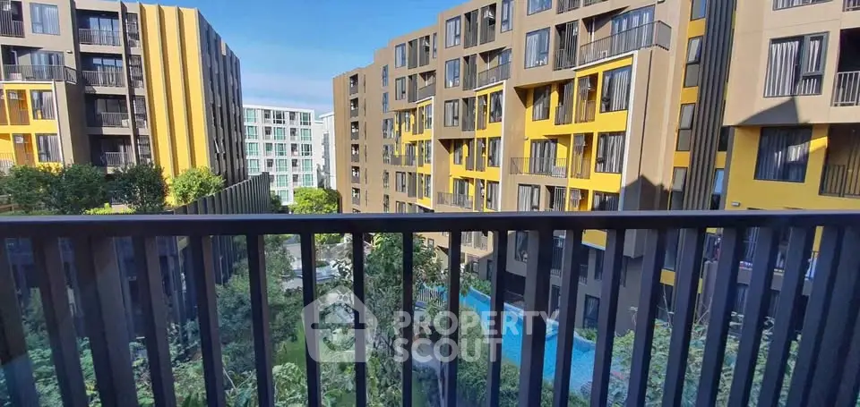 Modern apartment complex with vibrant yellow accents and lush greenery view.