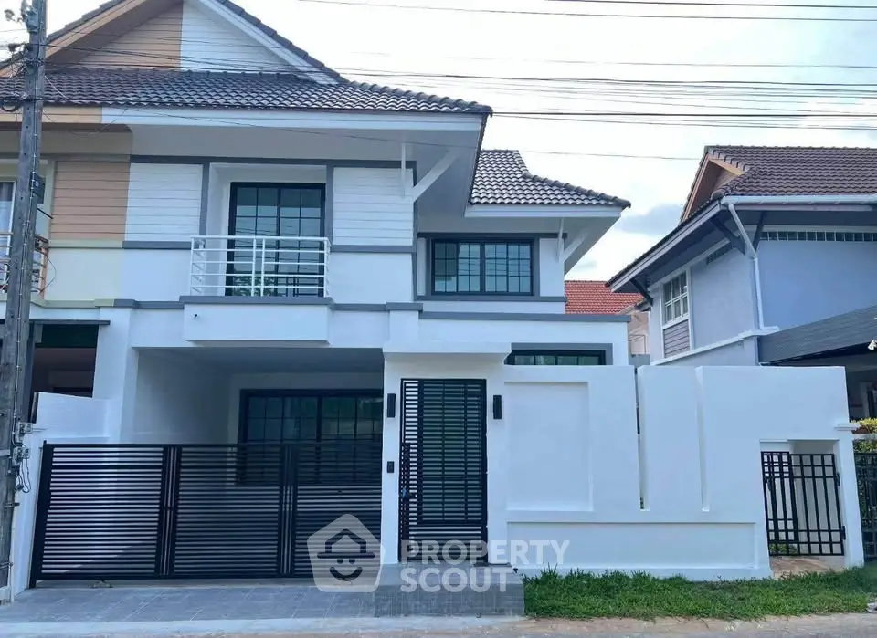 Modern two-story house with sleek design and gated entrance in a suburban neighborhood.