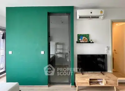 Modern living room with green accent wall, TV unit, and air conditioning, perfect for cozy urban living.