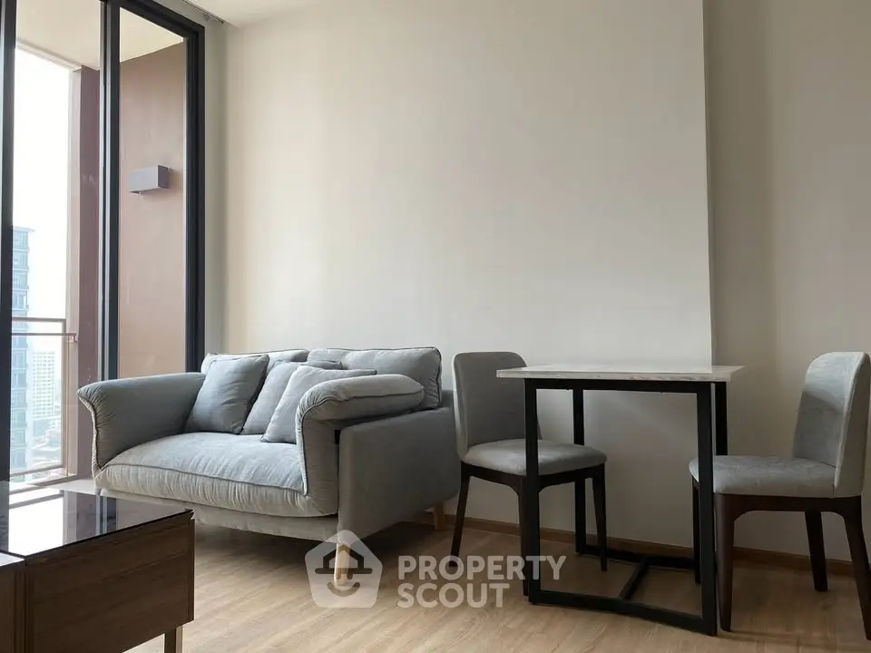 Modern living room with cozy sofa and dining table, featuring floor-to-ceiling windows and a city view.