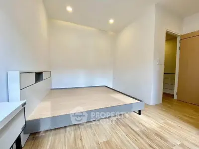 Spacious bedroom with modern design and wooden flooring in a minimalist apartment.