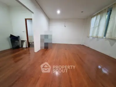 Spacious empty room with polished wooden floors and natural light, ideal for customization.