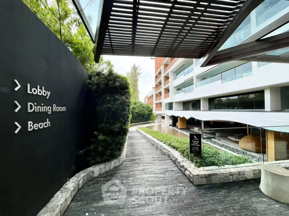 Luxurious hotel entrance with modern architecture and lush greenery leading to lobby, dining room, and beach.
