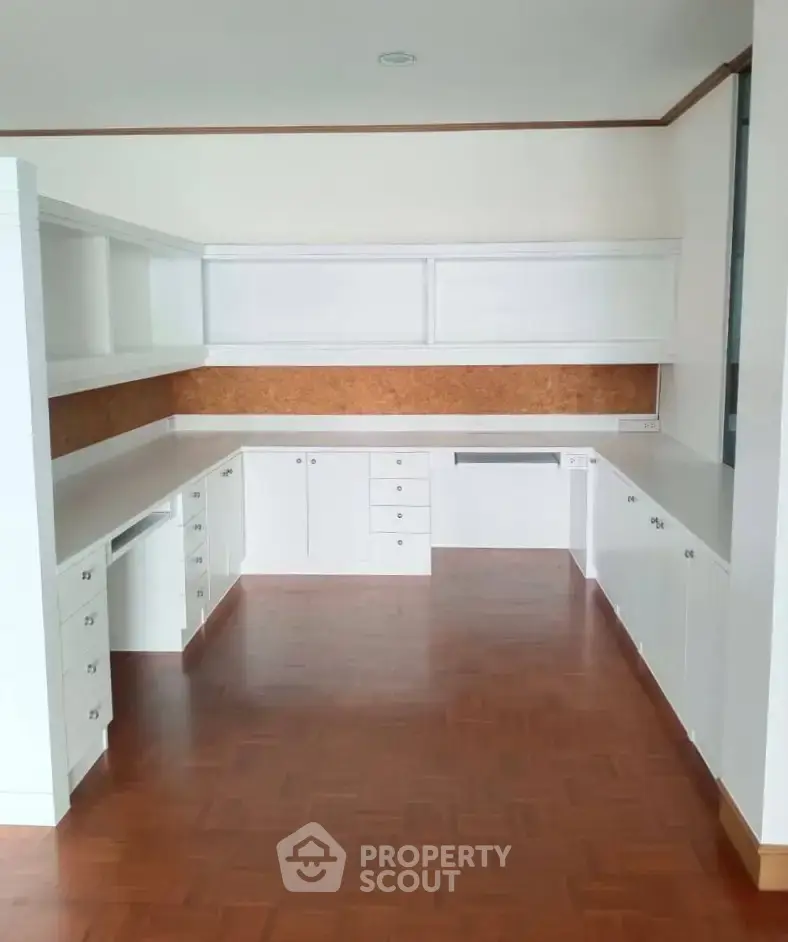 Spacious kitchen with white cabinetry and wood flooring, perfect for modern living.