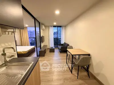 Modern open-plan apartment with kitchen, living area, and bedroom, featuring city views and stylish furnishings.