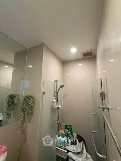 Modern bathroom with glass shower and sleek tile design, featuring contemporary fixtures and ample lighting.