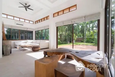 Spacious living room with natural light and garden view, featuring unique wooden furniture and modern design.