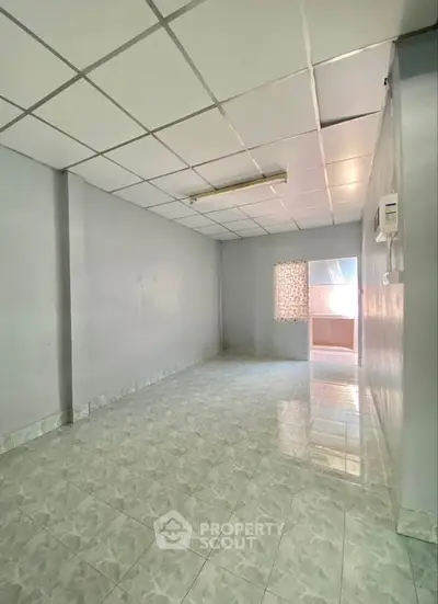 Spacious empty room with tiled flooring and natural light, ideal for customization.