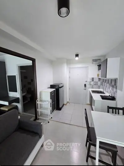 Modern open-layout kitchen and living area with sleek furniture and tiled flooring.