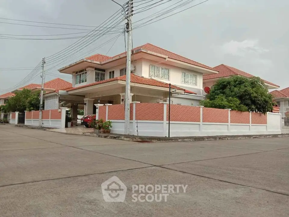 Charming two-story house with red-tiled roof and spacious fenced yard on a quiet street.