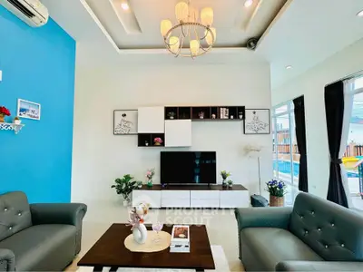 Luxurious living room with modern decor and pool view, featuring elegant chandelier and stylish furniture.