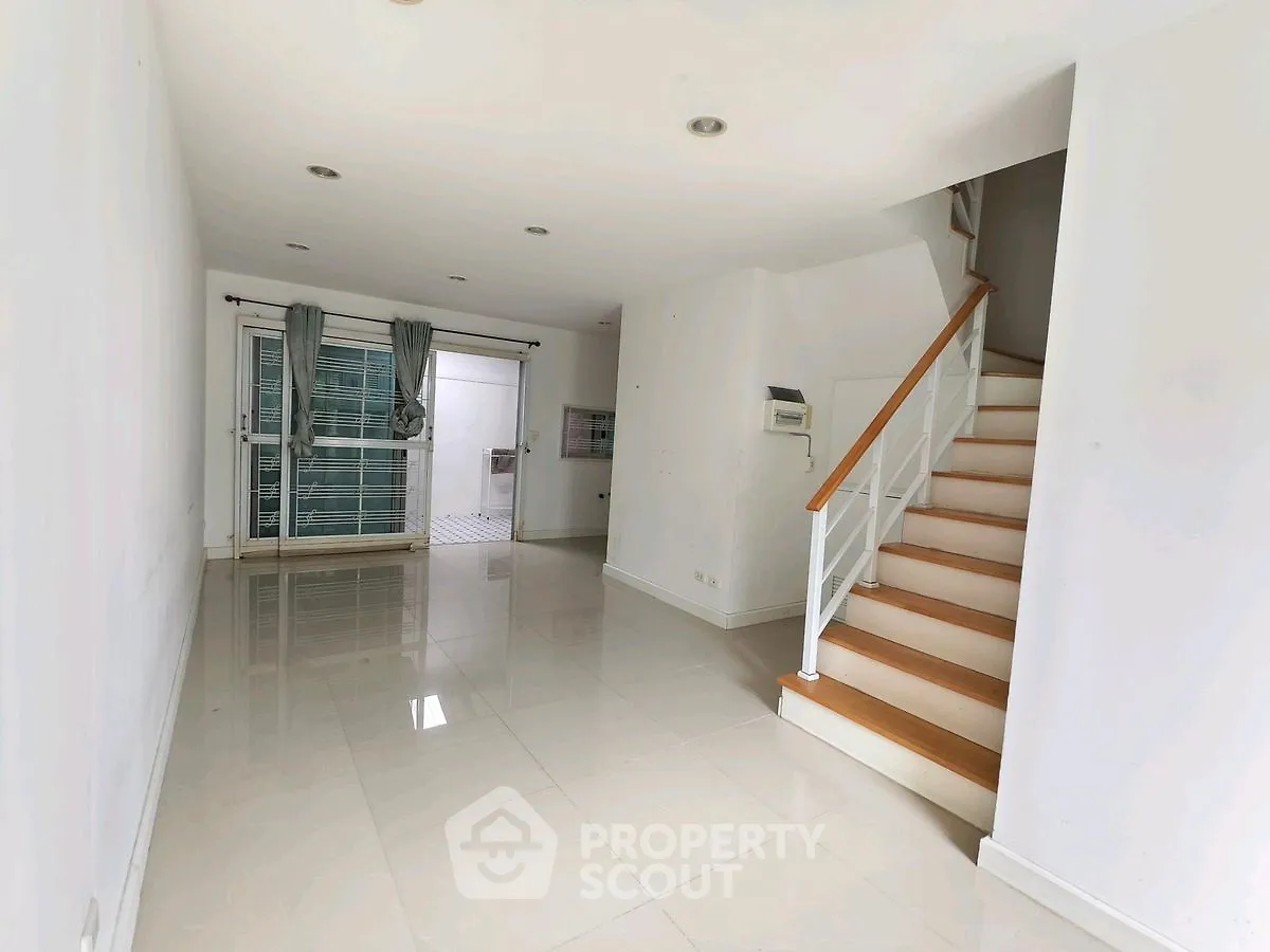 Spacious modern living room with glossy tile flooring and staircase, perfect for family gatherings.