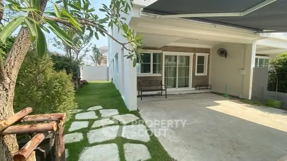 Charming house exterior with lush garden and cozy patio area.