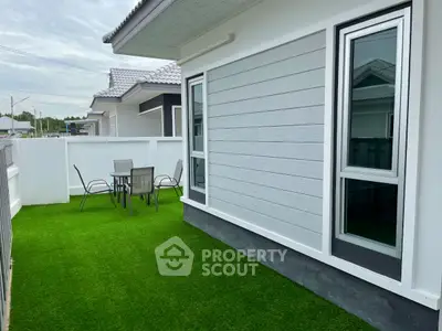 Charming modern house exterior with artificial grass and cozy patio area.