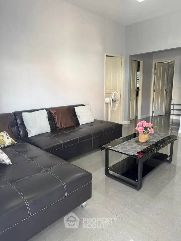 Modern living room with sleek black leather sofas and elegant glass coffee table