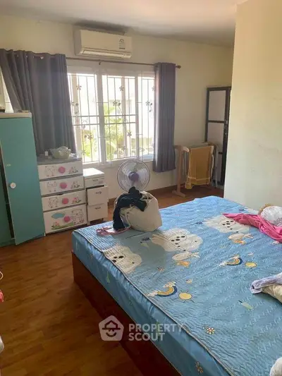 Cozy bedroom with wooden flooring and large window for natural light