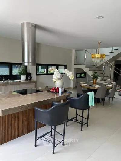 Luxurious open-plan kitchen with modern dining area and elegant staircase