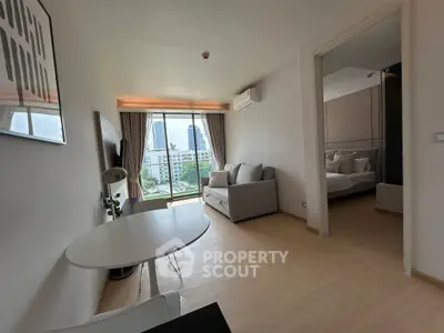 Modern apartment with open living room and city view, featuring sleek furniture and natural light.