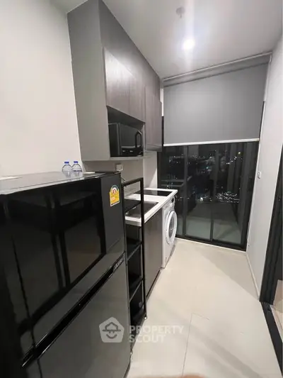 Modern kitchen with sleek appliances and city view, featuring fridge, microwave, and washing machine.