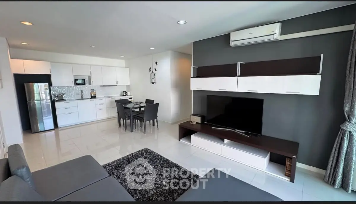 Modern open-plan living room with sleek kitchen, stylish furniture, and air conditioning in a contemporary apartment.