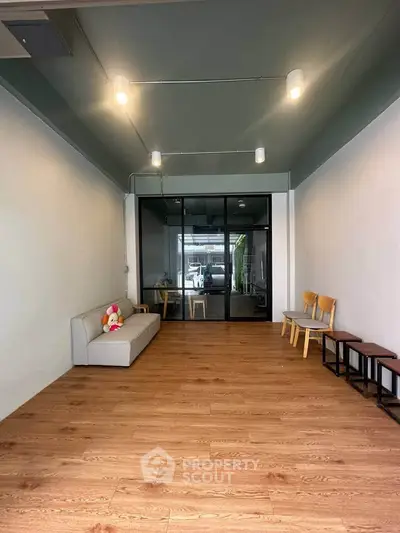 Spacious modern living room with wooden flooring and minimalist furniture, perfect for cozy gatherings.
