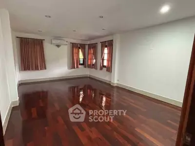 Spacious empty room with polished hardwood floors and large windows, perfect for customization.