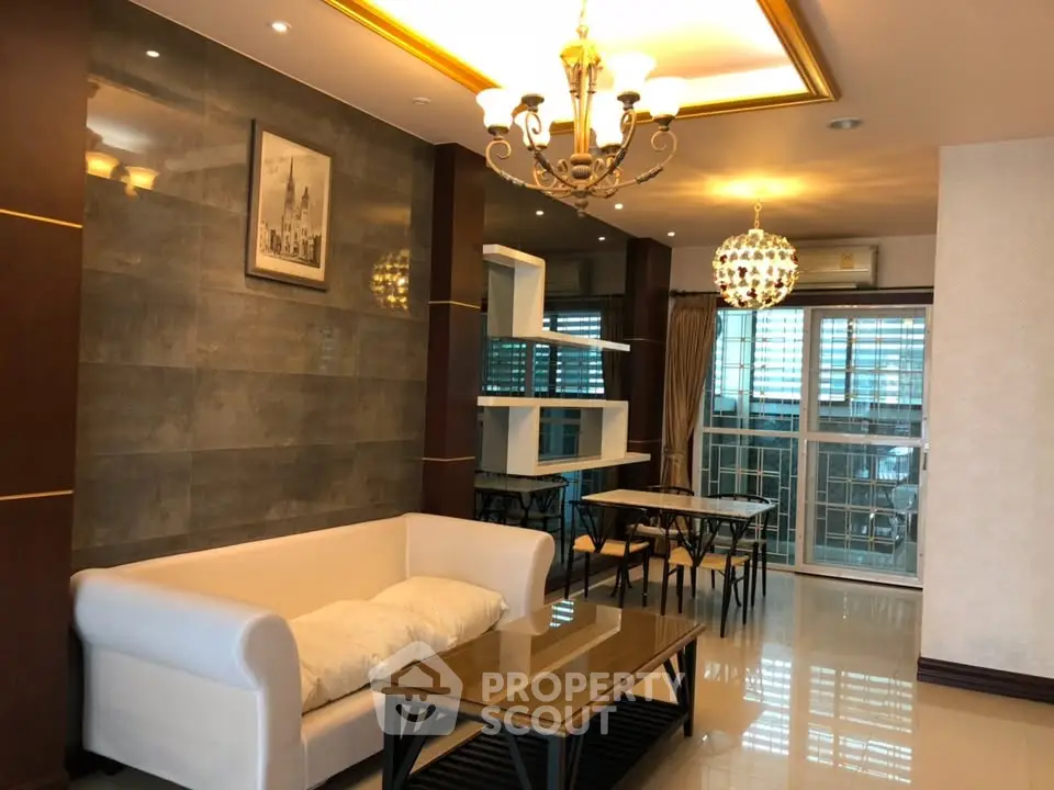 Elegant living room with modern chandelier and cozy seating area in a stylish apartment.