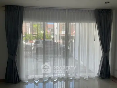 Spacious living room with large windows and elegant curtains, offering ample natural light.