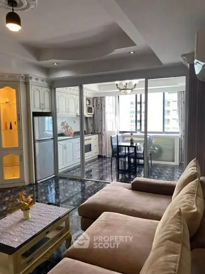 Spacious open-plan living room with modern kitchen and dining area, featuring elegant decor and ample natural light.