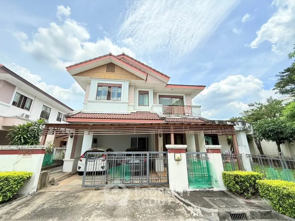 Charming two-story house with carport and lush greenery in a serene neighborhood.
