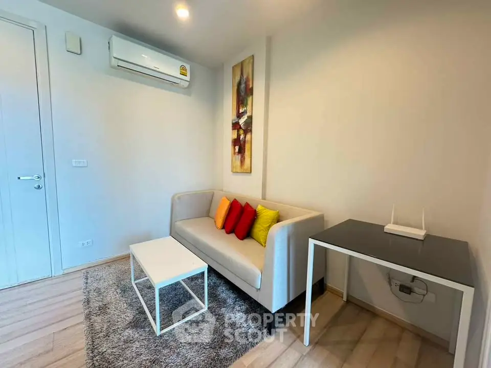 Modern living room with stylish sofa, colorful cushions, and sleek furniture in a cozy apartment.