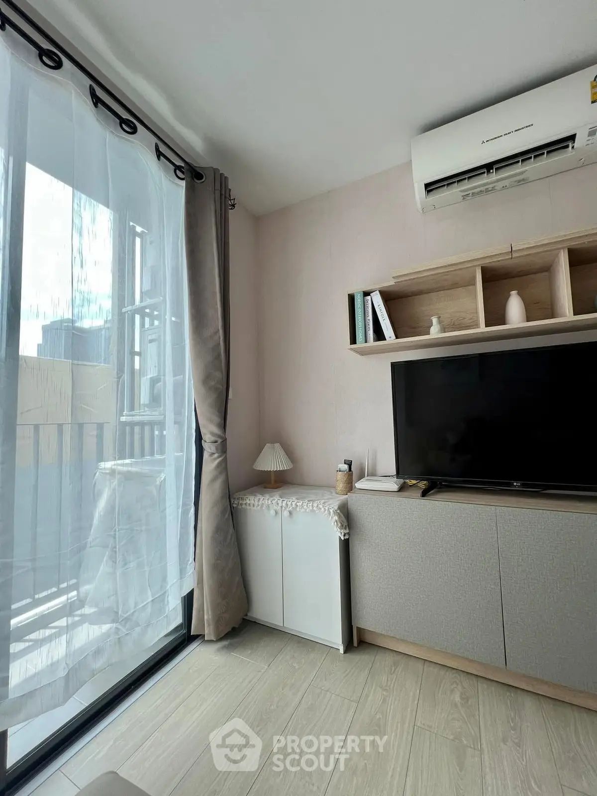 Modern living room with large window, air conditioning, and stylish shelving unit.