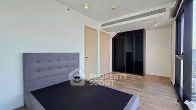 Spacious modern bedroom with large windows and sleek flooring in a contemporary apartment.