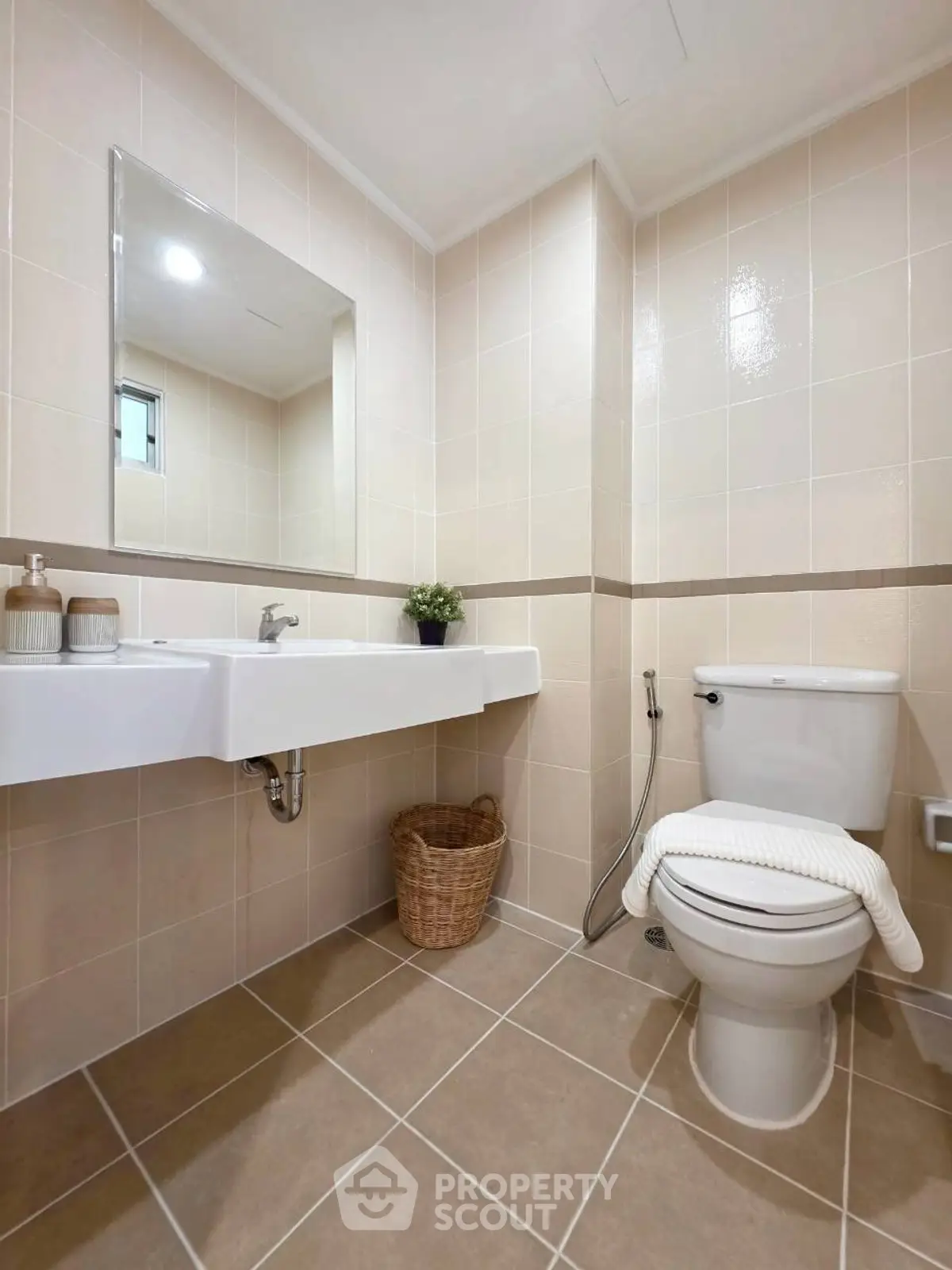 Modern bathroom with sleek fixtures and neutral tiles, featuring a stylish sink and toilet.