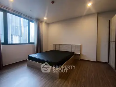 Spacious bedroom with modern design and large window offering city views.