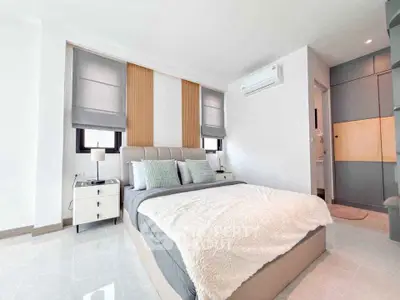 Modern bedroom with stylish decor and natural light, featuring a cozy bed and sleek furnishings.
