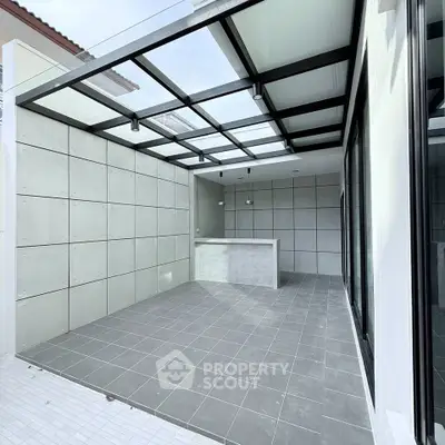 Modern outdoor patio with sleek concrete design and glass roof, perfect for entertaining.
