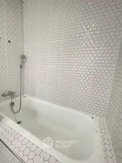 Modern bathroom with hexagonal white tiles and built-in bathtub