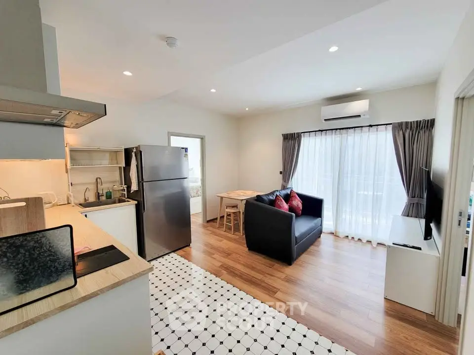 Modern open-plan living room with kitchen, featuring sleek appliances and stylish decor.