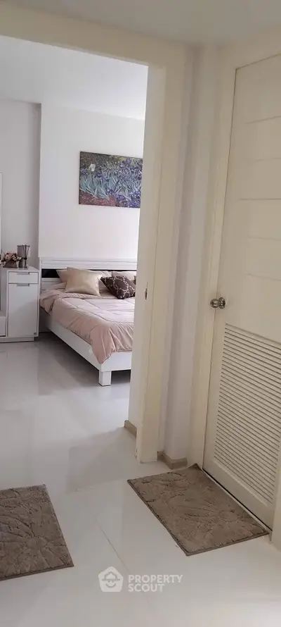 Modern bedroom with sleek white furniture and elegant decor, showcasing a serene and inviting atmosphere.