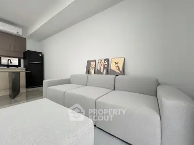 Modern living room with sleek gray sofa and minimalist kitchen design