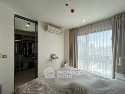 Modern bedroom with large window and walk-in closet in a stylish apartment.