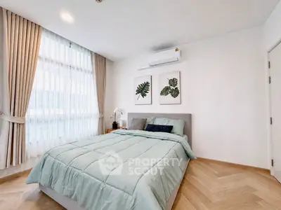 Modern bedroom with stylish decor and natural light, featuring elegant curtains and wooden flooring.