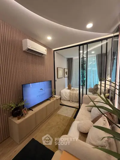 Modern living room with stylish decor and glass partition leading to a cozy bedroom.