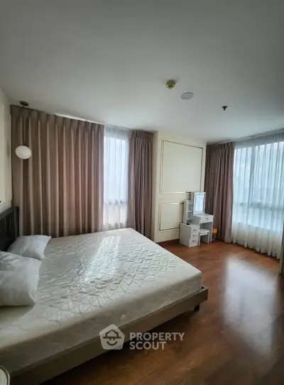 Spacious bedroom with elegant curtains and hardwood flooring