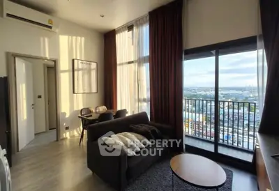 Modern living room with large windows and city view, featuring cozy seating and dining area.