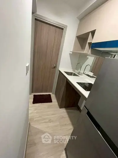 Compact modern kitchen with sleek cabinetry and stainless steel appliances in a cozy apartment.