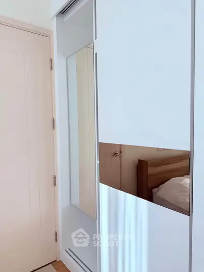 Modern bedroom with sleek wardrobe and wooden bed frame, showcasing minimalist design.