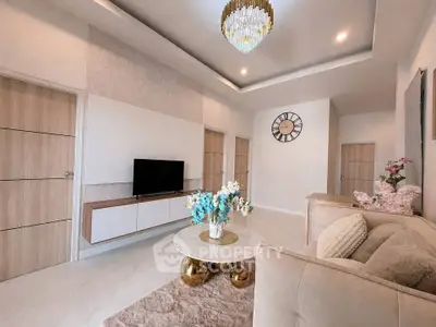 Elegant living room with modern decor, plush sofa, stylish chandelier, and wall-mounted TV in a cozy apartment.