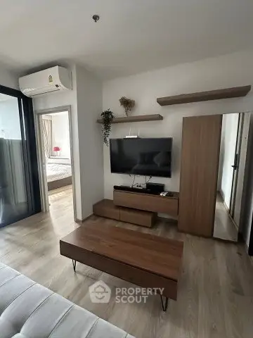 Modern living room with sleek wooden furniture and wall-mounted TV, adjacent to a cozy bedroom.